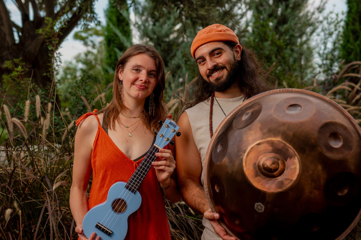 Véra and Emre, the duo Vemra, with a ukulele and a copper handpan in a garden