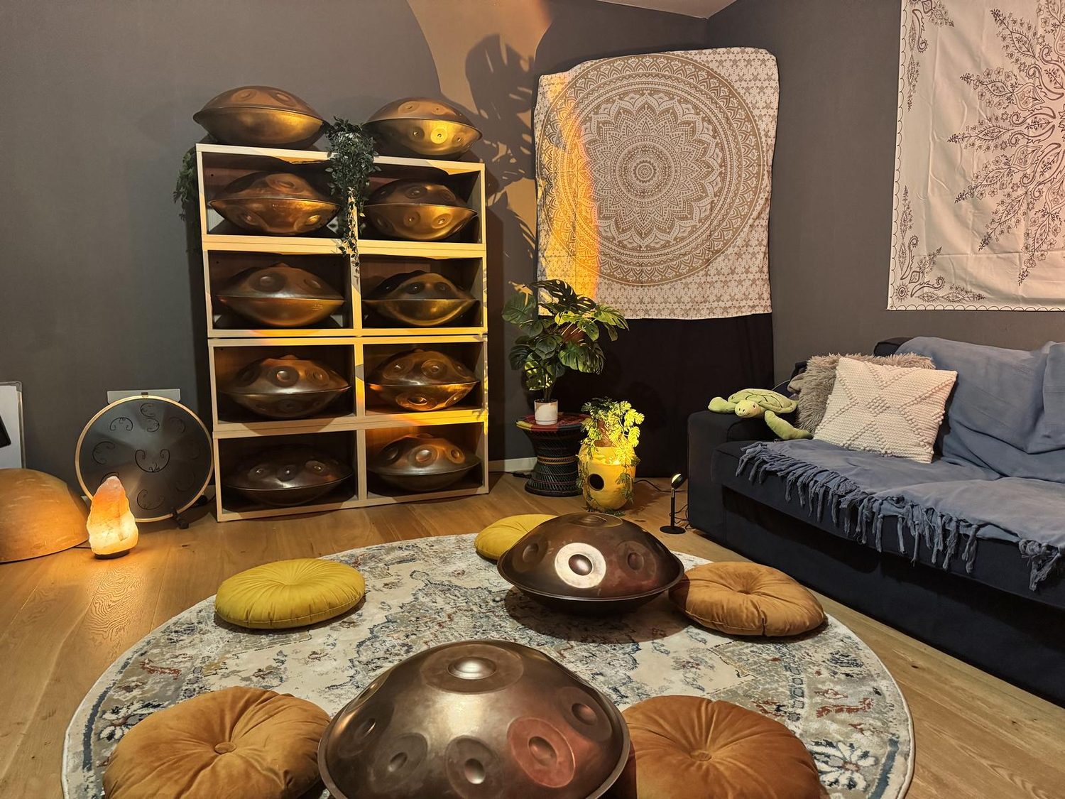 The studio: a shelf of handpans, a mandala on the wall, cushions on a round rug