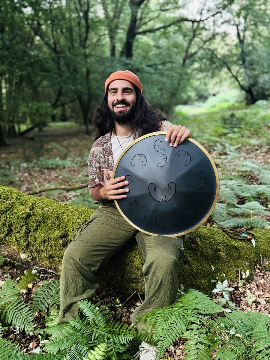 Emre holding a black tongue drum in the forest